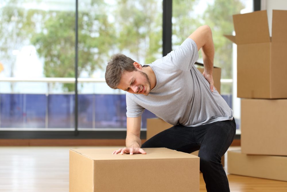 Man suffering back ache moving boxes