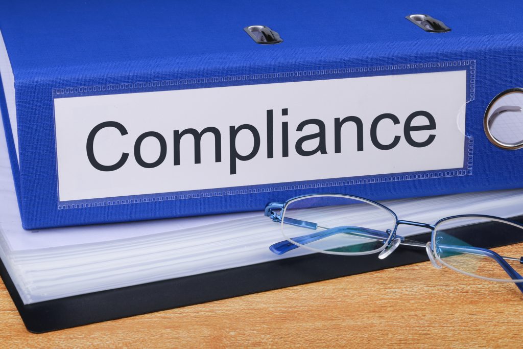 Office binder labelled “Compliance” with documents and safety records, supporting the topic “COSHH Compliance in the Workplace: What UK Employers Must Get Right to Stay Protected”, highlighting the importance of COSHH risk assessments, hazardous substance management, documentation, and ongoing monitoring to control exposure to harmful substances and meet UK health and safety regulations in workplace environments